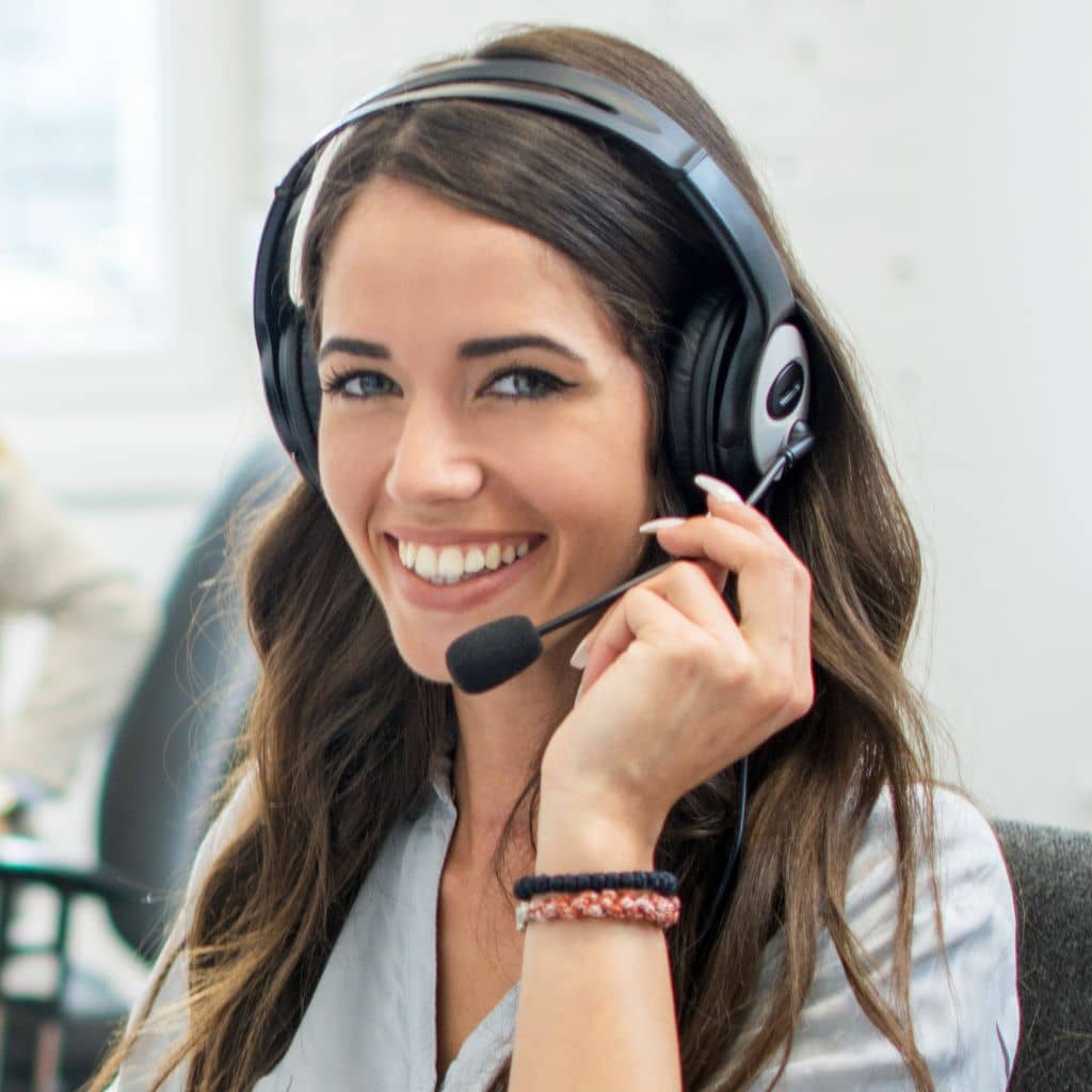 Frau telefoniert mit Headset und lacht in die Kamera