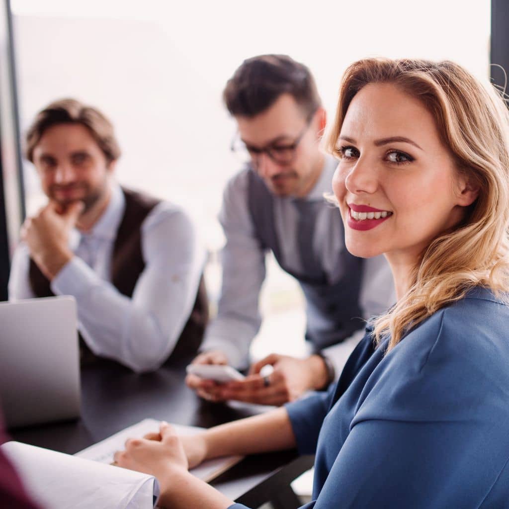 Eine Frau und zwei Männer lächeln in die Kamera