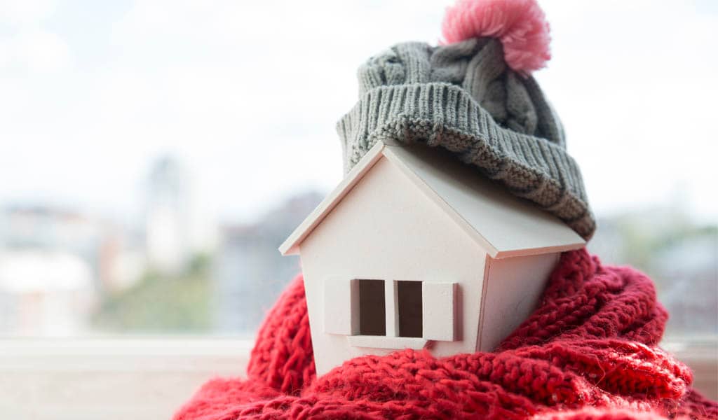 Mini Holzhäuschen mit Mütze und in Schal eingewickelt